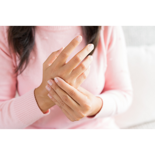 woman in pink shirt holding painful right hand from inflammation
